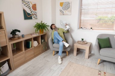 Evde elektrikli yelpazesi olan genç bir adam var.