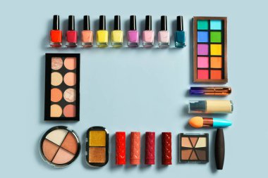 Mavi arkaplanda farklı dekoratif kozmetiklerden yapılmış çerçeve