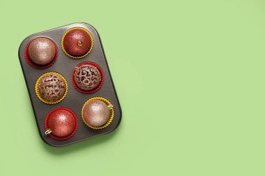 Yeşil arka planda güzel Noel topları olan kek tepsisi