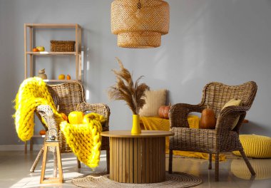 Sehpanın üzerinde hasır koltuklar, balkabakları ve pampalar olan sonbahar içleri.