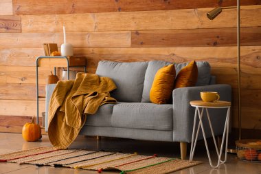 Gri kanepe, balkabağı ve rahat battaniyeli bir sonbahar salonu.