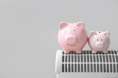 Evdeki beyaz duvarın yanındaki elektrikli konteyner ısıtıcısının kumbarası. Isıtma kaydetme kavramı