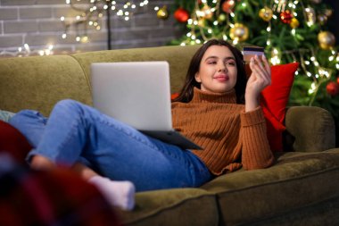 Bilgisayarlı ve kredi kartlı genç bir kadın Noel için internette alışveriş yapıyor.