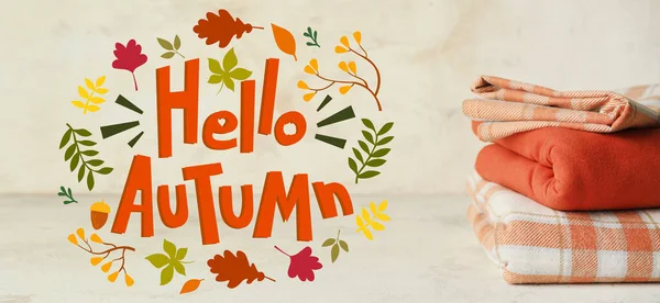 Banner with stack of warm clothes and text HELLO, AUTUMN