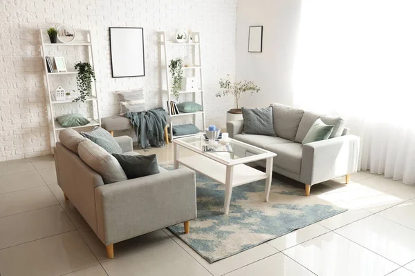 Interior of light living room with cozy grey sofas and coffee table