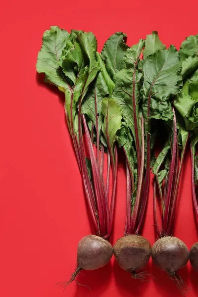 Fresh beetroots with leaves on red background
