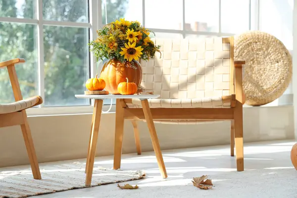 Pumpkins with autumn bouquet on table in living room