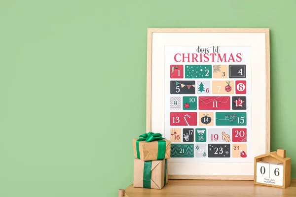 Christmas calendars with presents on shelf near green wall