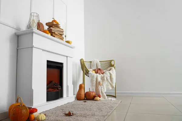 Autumn interior of living room with fireplace, stylish armchair and pumpkins