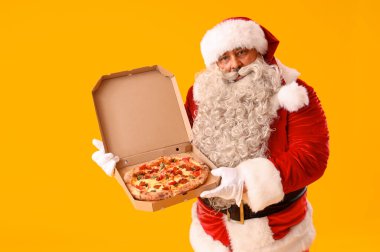 Sarı arka planda lezzetli pizzalı Noel Baba