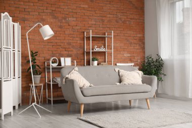 Modern oturma odasının içindeki yastıklı rahat gri kanepe.