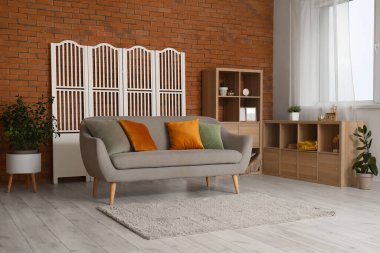 Modern oturma odasının içindeki yastıklı rahat gri kanepe.