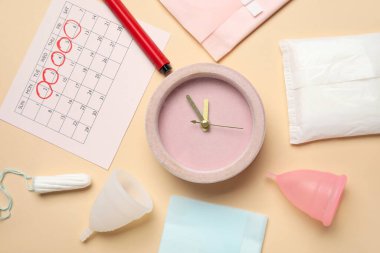 Composition with alarm clock, menstrual calendar and different feminine hygiene products on color background clipart