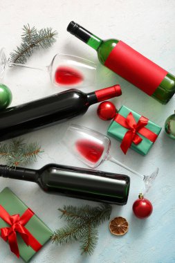 Şişeler ve bardaklar dolusu şarap açık mavi arka planda Noel hediyesi kutuları