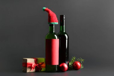 Noel topları ve siyah arka planda hediye kutusu olan bir şişe şarap.