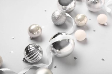 Kurdeleli gümüş Noel baloları ve beyaz arka planda konfeti.