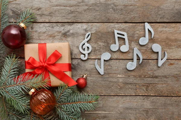 Composition with music signs, Christmas decorations and gift box on wooden background