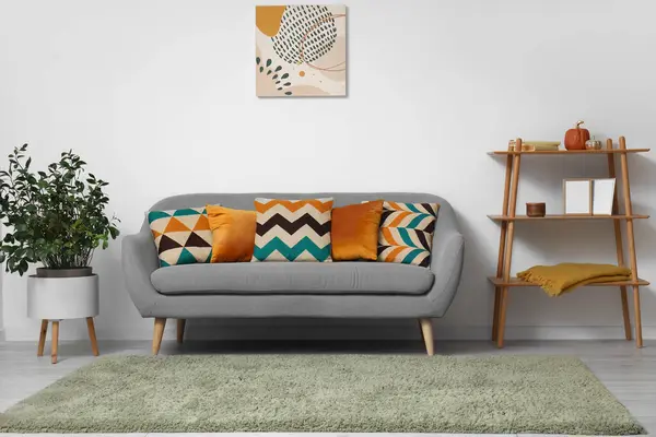 Interior of modern living room with grey sofa, cushions and houseplant