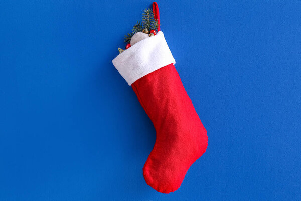 Рождественский носок висит на ветке елки и шары на синем фоне