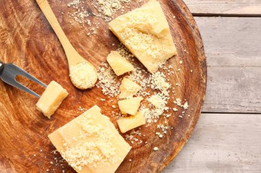 Hafif ahşap arka planda lezzetli parmesan peyniri parçaları olan tabak, yakın plan.