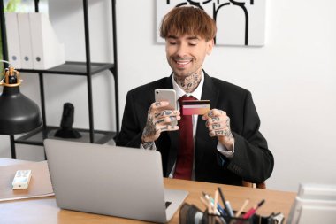 Ofiste cep telefonu kullanan genç bir işadamı.