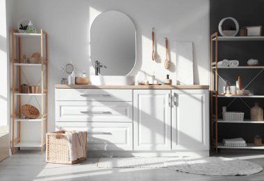 Lavabolu, aksesuarlı ve aynalı bir banyo.