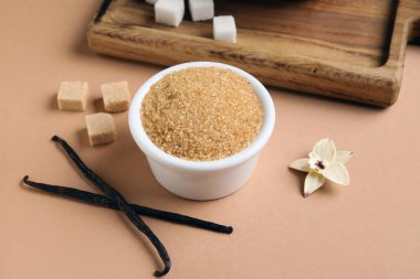 Kahverengi arka planda aromatik vanilya şekeri, çiçek ve çubuklarla dolu bir kase