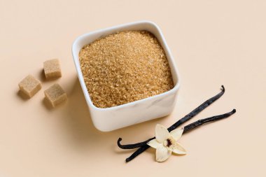 Aromatik vanilya şekeri, çiçek ve bej arka planda çubuklar olan bir kase.