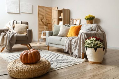 Gri kanepesi, koltuğu ve kabağı hasır pouf üzerinde olan şık bir oturma odası.