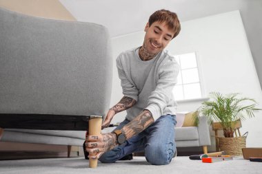 Genç adam evde koltuk topluyor.