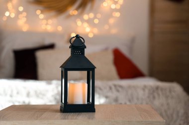 Yatak odasındaki masada yanan mum olan Noel feneri, yakın plan.