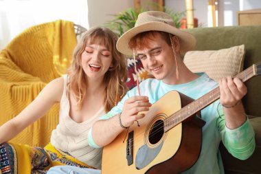 Evde gitar çalan iki hippi.