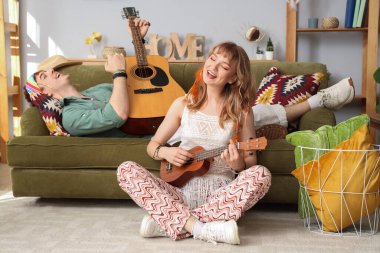 Birkaç hippi evde gitar çalıyor.