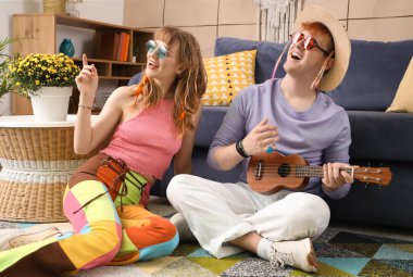 Birkaç hippi evde ukulele oynuyor.