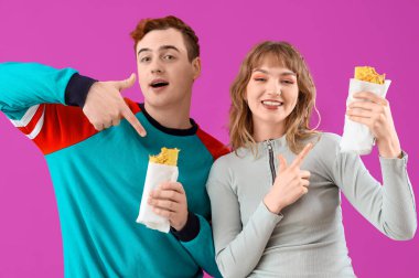 Genç çift mor arka planda lezzetli sandviç paketlerine işaret ediyor.