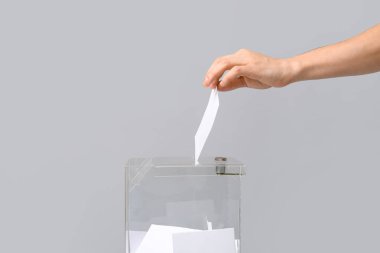 Açık arkaplanda oy sandığının yanındaki oy veren adam