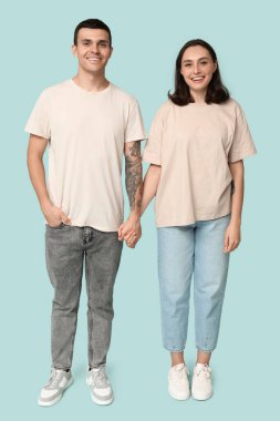 Mavi arka planda el ele tutuşan genç çift