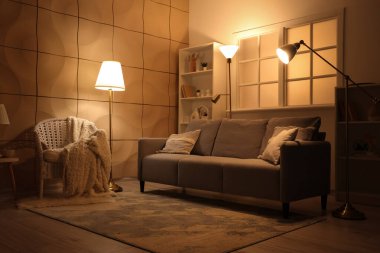 Akşamları kanepede ve parlak lambaları olan karanlık oturma odasının içinde.