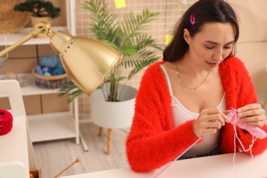 Evde iğnelerle örgü ören genç bir kadın.