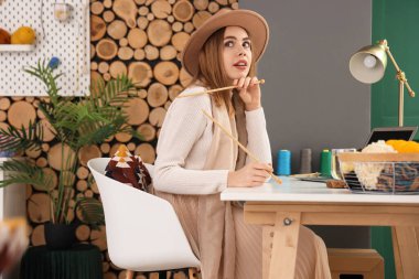 Evde örgü şişleri olan düşünceli genç bir kadın.