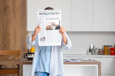 Mutfakta gazetesi olan genç bir adam.