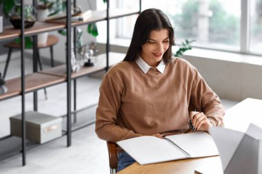 Masada defterle çalışan güzel bir iş kadını.
