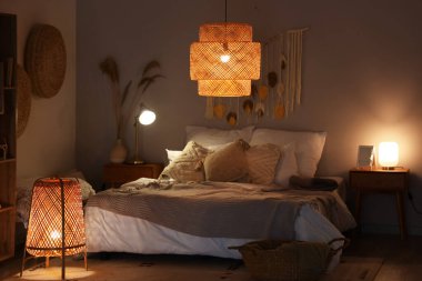 Yatak odasının içinde, yatakta battaniyeler ve akşam lambaları var.