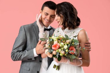 Pembe arka planda bir buket çiçekleri olan genç bir çift.