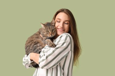 Yeşil arka planda sevimli tekir kedisi olan güzel genç bir kadın.