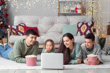 Patlamış mısırlı mutlu bir aile evde dizüstü bilgisayardan Noel filmi izliyor.