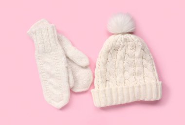 Pembe arka planda sıcak şapkalı bir çift beyaz eldiven.