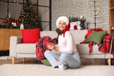 Genç bir kadın Noel arifesinde sıcak kakao içiyor.