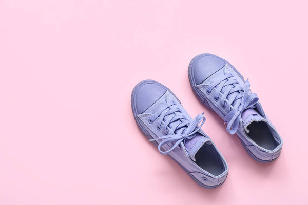 Pair of stylish child's gumshoes on pink background