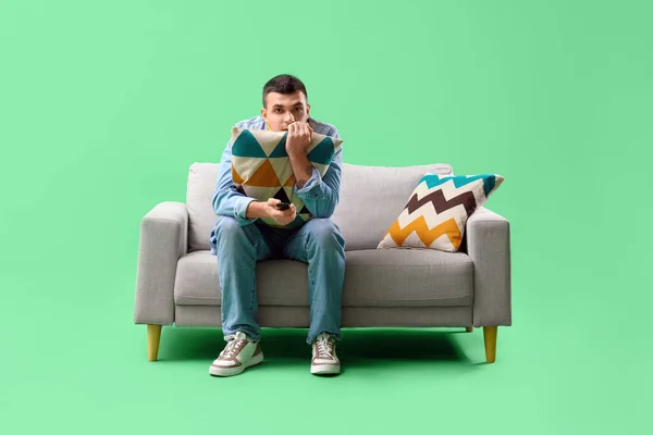 Junger Mann Schaut Auf Sofa Vor Grünem Hintergrund Fern — Stockfoto